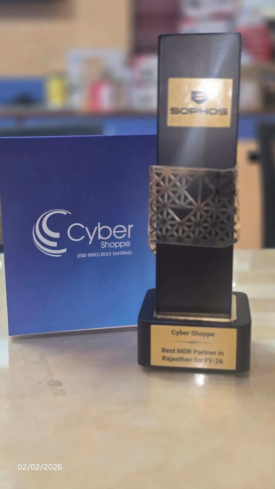 A black and gold Sophos trophy engraved "Cyber Shoppe, Best MDR Partner in Rajasthan for FY-26", standing beside a Cyber Shoppe folder.