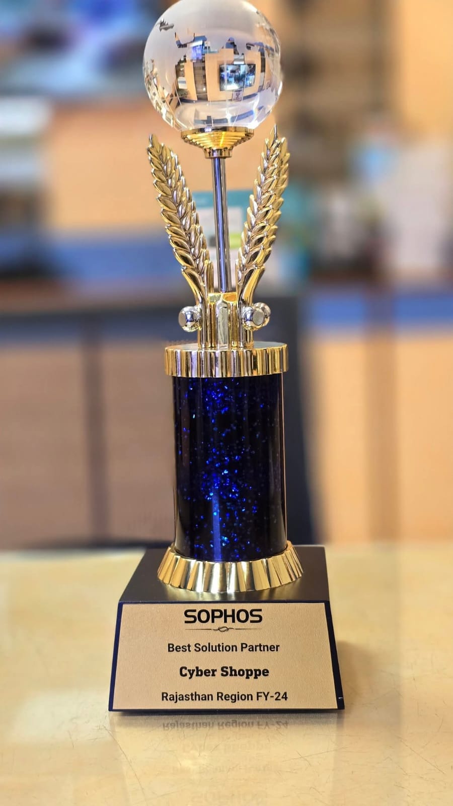 A crystal globe trophy on a blue and gold column, plaque reading "Sophos, Best Solution Partner, Cyber Shoppe, Rajasthan Region FY-24".